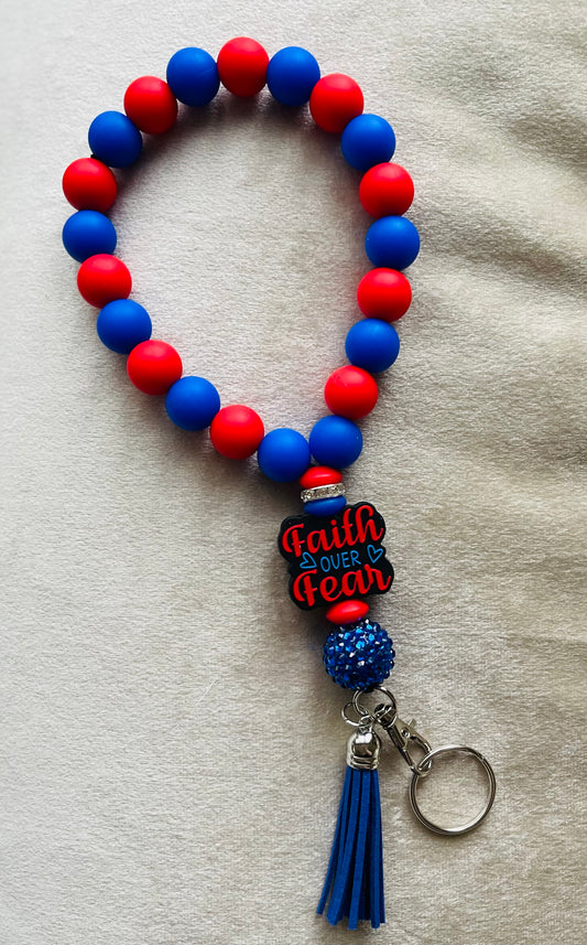Beaded wristlet keychain with 'Faith Over Fear' charm focal bead made with red and blue silicone beads and a blue tassel with a blue sparkle ball charm