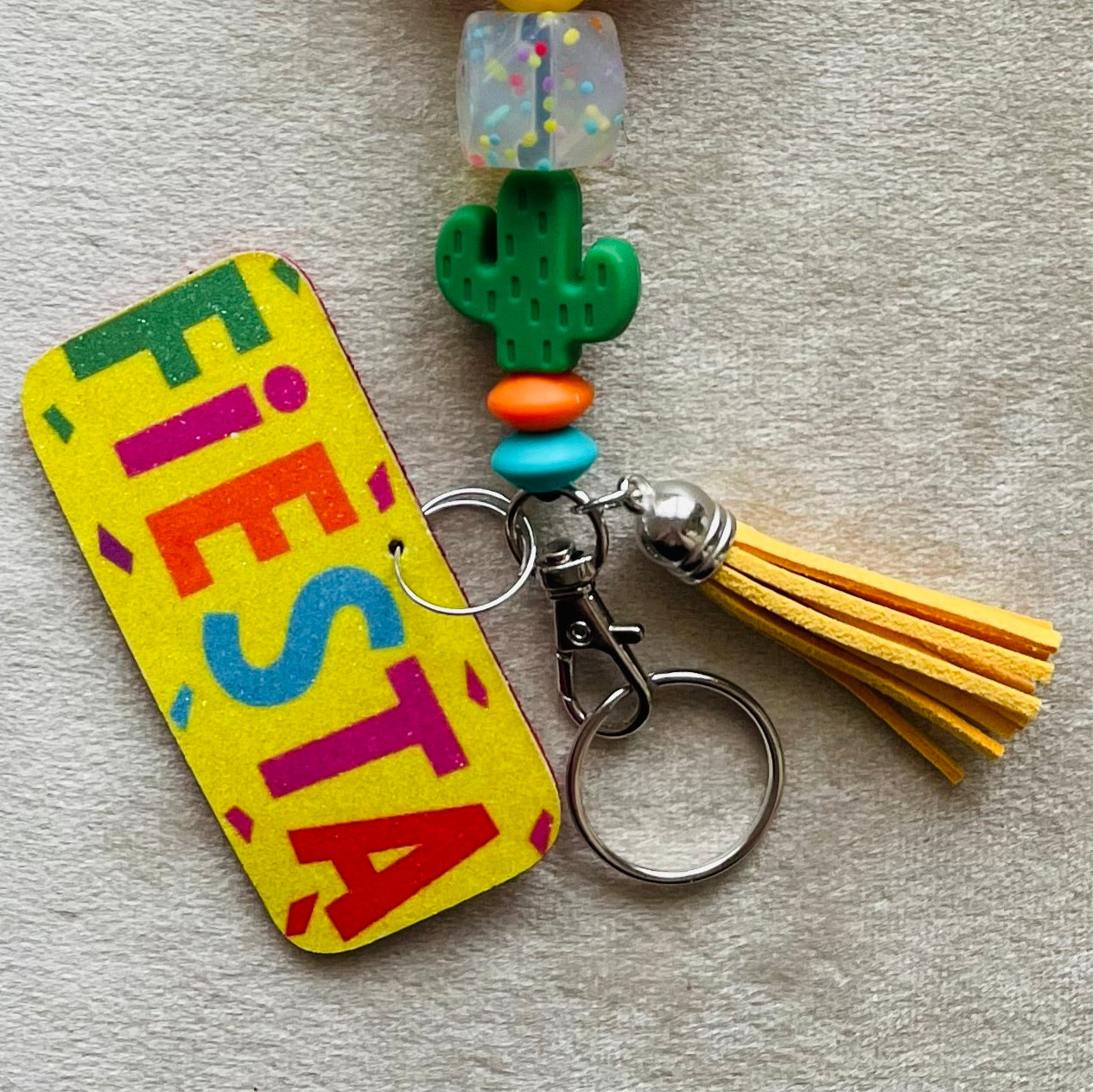 Colorful 'Fiesta' keychain with cactus charm and tassel on a light gray background