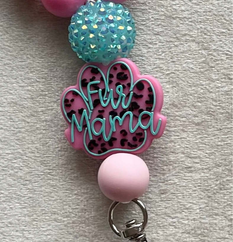 Pink wristlet keychain with 'Fur Mama' text and teal glittery ball made with light pink silicone beads.