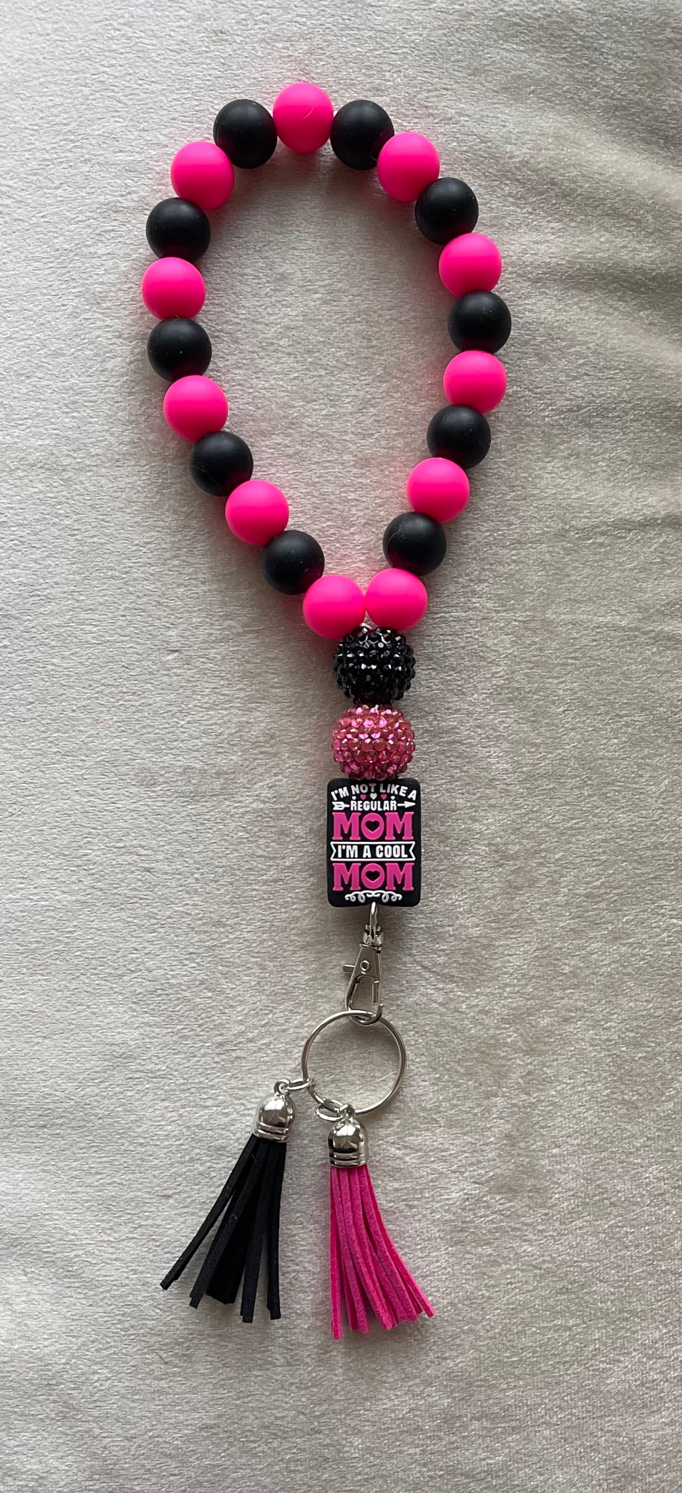 Hot pink and black silicone beads with hot pink and black tassels wristlet keychain with "Mean Girls" movie quote. "I'm not like a regular mom, I'm a cool mom" text on a silicone focal bead. Bling beads